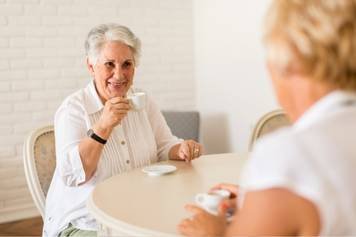 A photo of a female audiologist providing a hearing aid consultation to a middle-aged male client with brown skin and a beard.