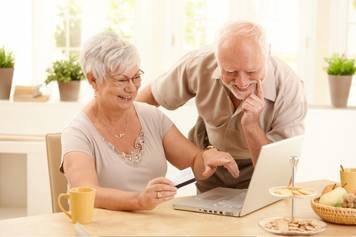 A photo of a female audiologist providing a hearing aid consultation to a middle-aged male client with brown skin and a beard.